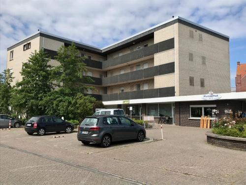 a building with two cars parked in a parking lot at Apartment CAPTAIN'S LODGE in Norddeich