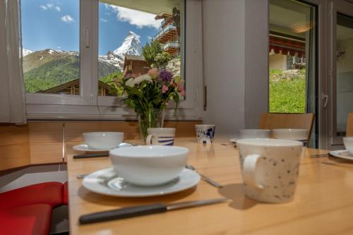 a table with cups and a vase of flowers on it at Haus Sonnheim in Zermatt