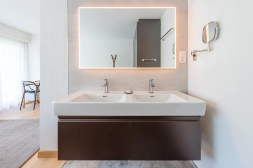 y baño con lavabo blanco y espejo. en Haus Sonnheim, en Zermatt
