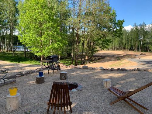 a fire pit in a park with two chairs and a grill at Auksinio elnio slėnis in Rukliai