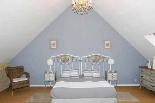 una camera da letto con un letto e un lampadario di Les Pérelles a Saint-Vigor-le-Grand