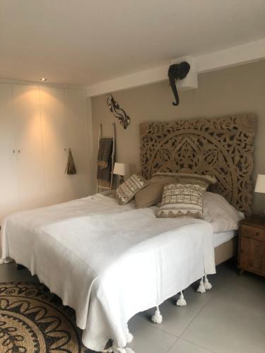 - une chambre avec un grand lit blanc et une tête de lit en bois dans l'établissement La Casita Alta Free Parking, à Noordwijk aan Zee