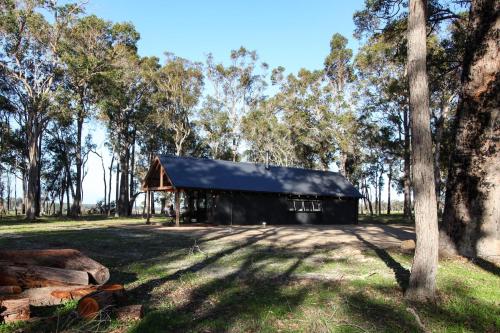 a black barn in a field with trees at Littlewood Chalet in Margaret River Town