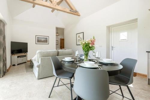 a dining room with a table and chairs and a couch at Barrow Hill Barns in Petersfield
