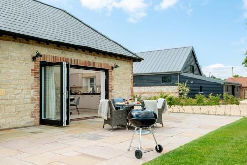 a patio with a grill in front of a house at Barrow Hill Barns in Petersfield