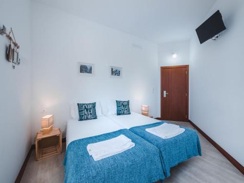 a bedroom with a bed with blue bedspread and two towels at Nature Madeira Guest House in Porto da Cruz