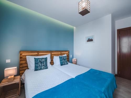 a bedroom with a large bed with blue walls at Nature Madeira Guest House in Porto da Cruz