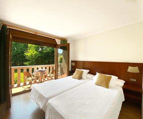 two beds in a hotel room with a balcony at Hotel EntreRobles in Baiona