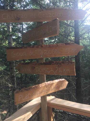 a sign in the woods with many signs on it at cabane de l'Ecureuil in Châtel-Guyon