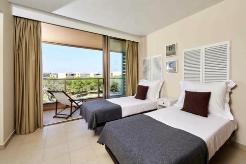 um quarto de hotel com duas camas e uma varanda em Apartamento T2 Herdade dos Salgados em Albufeira