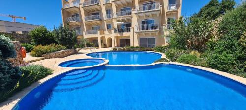 a large blue swimming pool in front of a building at Il Bejta penthouse in Qala