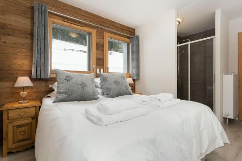 une chambre avec un lit avec des draps blancs et des oreillers dans l'établissement Le Mont Royal - Apt A104 - Châtel, à Châtel