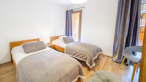 une chambre avec deux lits et une chaise et une fenêtre dans l'établissement Les 4 Elements - Apt C102 - BO Immobilier - Châtel, à Châtel