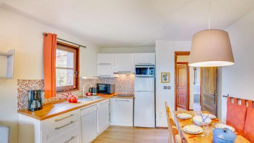 a kitchen with white cabinets and a dining table at Tovassiere - Apt B115 - BO Immobilier in Châtel