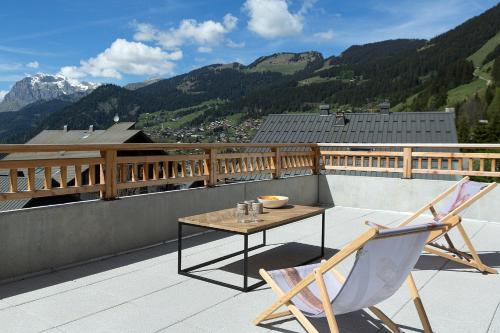 d'une table et de chaises sur un balcon avec vue sur les montagnes. dans l'établissement Le Mont Royal - Apt A104 - Châtel, à Châtel