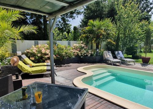 una piscina en un patio trasero con mesa y sillas en Les Centauris en Pléguien