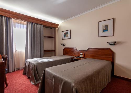 um quarto de hotel com duas camas e uma janela em Hotel Nacional em Lisboa