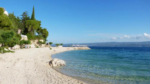 a sandy beach with trees and the water at Nemira beach apartments in Omiš