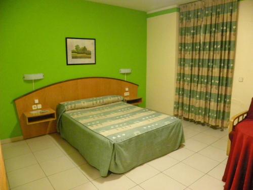 um quarto com uma cama e uma parede verde em Hostal Las Fuentes em Arévalo