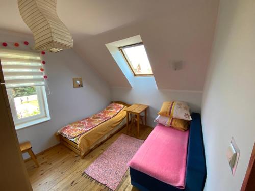 a attic bedroom with two beds and a window at Dom pod Jabłonia in Stare Juchy