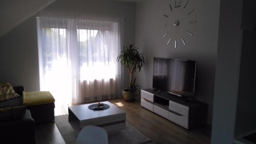 a living room with a television and a clock on the wall at Apartament Słoneczny in Gdańsk