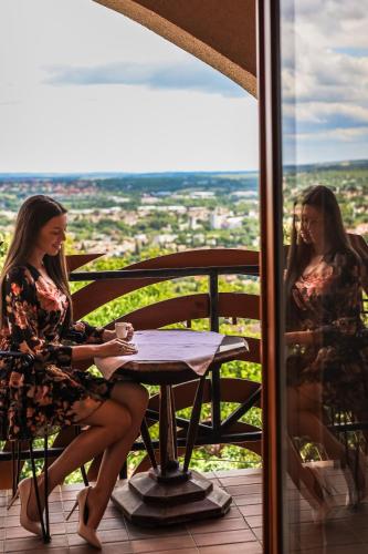 two women sitting at a table on a balcony at Bagolyvár Panzió in Pécs