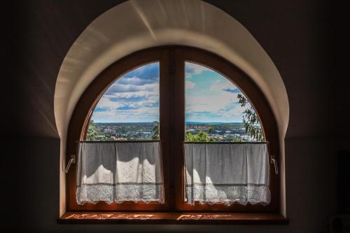 une fenêtre cintrée avec vue sur la ville dans l'établissement Bagolyvár Panzió, à Pécs