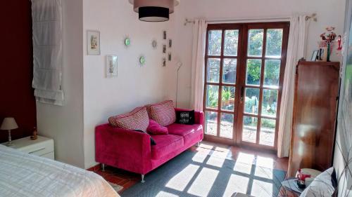 a living room with a pink couch and a bed at La Chambre de Ker Briac in Funchal