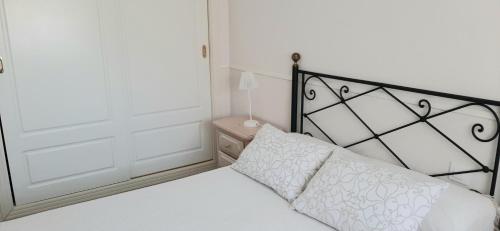 a bedroom with a bed with a white pillow and a door at Apartamento Realengo Sevilla in Seville