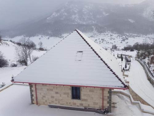 a building covered in snow with mountains in the background at JOEN Village in Librazhd