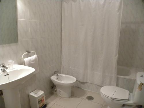 uma casa de banho com um lavatório, um WC e uma cortina de chuveiro. em Hostal Las Fuentes em Arévalo