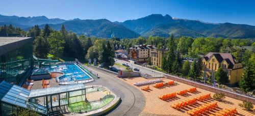 a resort with a pool and mountains in the background at Kompleks Antałówka Termy & Med in Zakopane