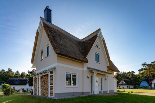 uma casa branca com um telhado preto em Luxusferienhaus Fuchsbau - mit Netflix, PlayStation, Sauna, Sportraum und Kamin em Zirchow