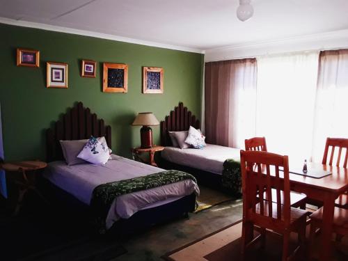 two beds in a room with green walls at Dullstroom on the Dam in Dullstroom