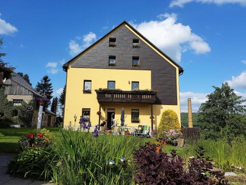 クアオルト・オーバーヴィーゼンタールにあるFerienwohnungen "Am Schlössel"の黒屋根の大黄色い家
