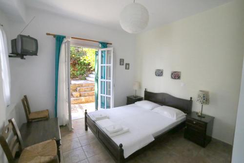 a bedroom with a bed and a tv and a window at Studios Argyri in Agios Kirykos