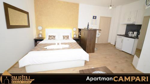 a bedroom with a large bed and a kitchen at Apartman Campari in Banja Luka