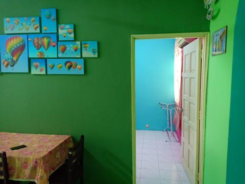 a green room with a table and a door at Adiana Homestay in Kuah