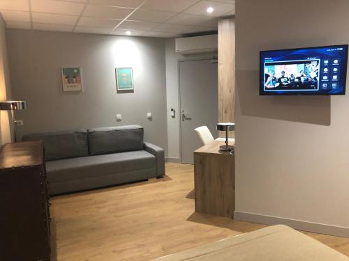 a living room with a couch and a flat screen tv at Hotel Victor Hugo in Toulouse