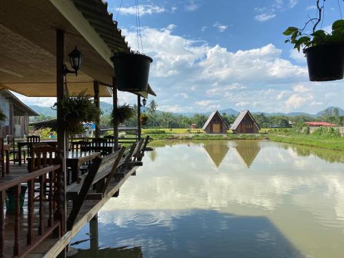 a view of a body of water with benches and houses at Huean Himbo in Chiang Rai