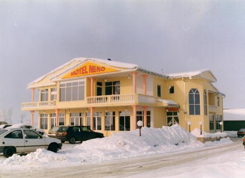 un gran edificio amarillo con nieve delante en Motel Neno, en Bijeljina