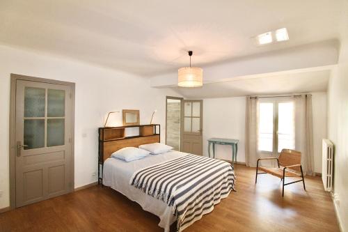 een witte slaapkamer met een bed en een stoel bij Grand appartement avec vue sur quai in Sète