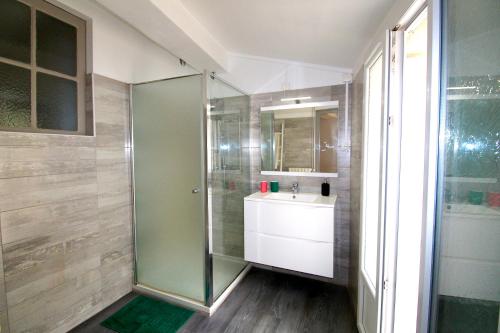 y baño con ducha acristalada y lavamanos. en Grand appartement avec vue sur quai en Sète