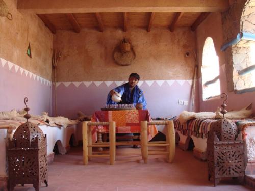 un hombre sentado en una mesa en una habitación en Gite Kasbah Tiznit, en Tiznit