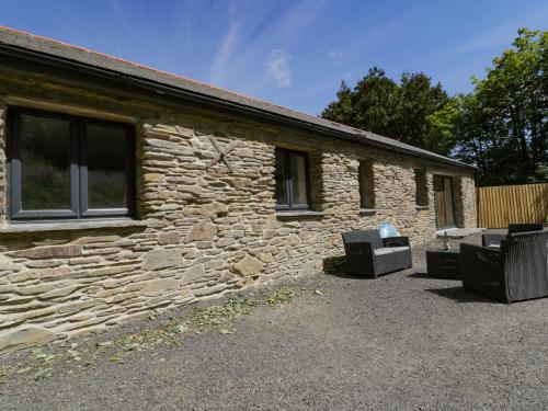 a stone house with two chairs and a building at The Cart House in St Austell