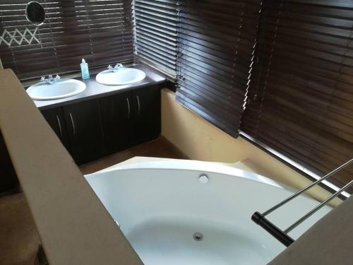 a bathroom with two sinks and a bath tub at Sunset Private Game Lodge Mabalingwe in Warmbaths