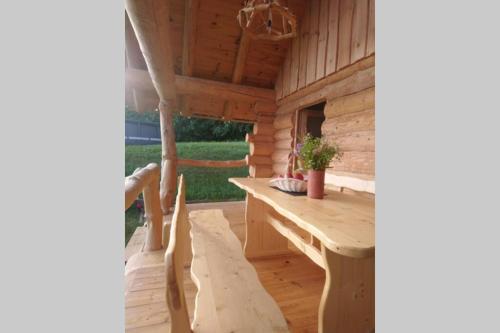 a wooden porch with a wooden table and bench at Hut at the forest in Male Brusnice