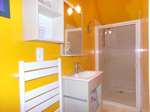 een badkamer met gele muren, een wastafel en een douche bij Doubs Séjour - Maison de vacances in Verdun-sur-le-Doubs