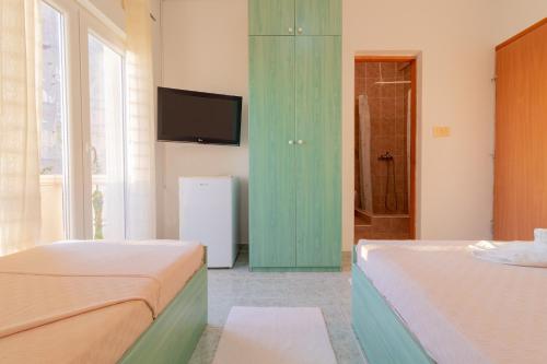 a bedroom with two beds and a television on a wall at Room Dragičević with Garage in Budva