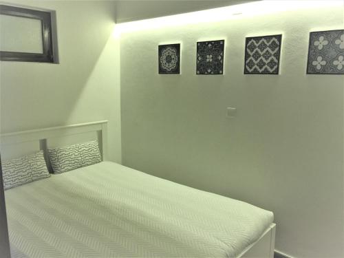 1 cama en una habitación con 3 cuadros en la pared en Seaside Apartment, en Sesimbra